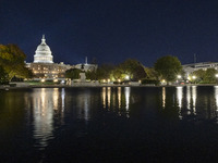 Night view with dark sky of the illuminated US Capitol reflecting on the pool water surface. The Capitol is the seat of the United States Co...