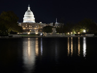 Night view with dark sky of the illuminated US Capitol reflecting on the pool water surface. The Capitol is the seat of the United States Co...