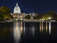 Night view with dark sky of the illuminated US Capitol reflecting on the pool water surface. The Capitol is the seat of the United States Co...