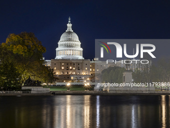 Night view with dark sky of the illuminated US Capitol reflecting on the pool water surface. The Capitol is the seat of the United States Co...