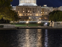 Night view with dark sky of the illuminated US Capitol reflecting on the pool water surface. The Capitol is the seat of the United States Co...