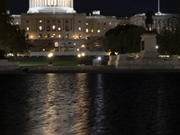 Night view with dark sky of the illuminated US Capitol reflecting on the pool water surface. The Capitol is the seat of the United States Co...