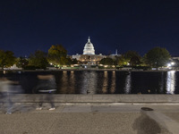 Night view with dark sky of the illuminated US Capitol reflecting on the pool water surface. The Capitol is the seat of the United States Co...