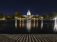 Night view with dark sky of the illuminated US Capitol reflecting on the pool water surface. The Capitol is the seat of the United States Co...