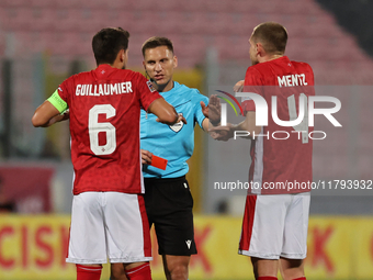 In Ta' Qali, Malta, on November 19, 2024, UEFA appoints match referee Luka Bilbija (center) to speak to Matthew Guillaumier of Malta during...