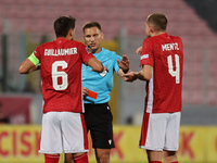 In Ta' Qali, Malta, on November 19, 2024, UEFA appoints match referee Luka Bilbija (center) to speak to Matthew Guillaumier of Malta during...