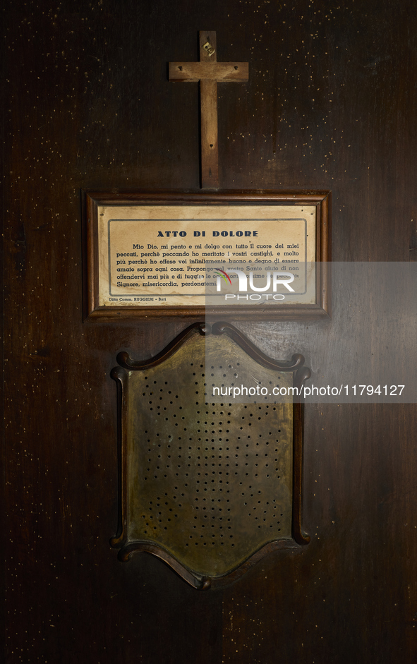 This image shows the exterior of a confessional in the crypt of the San Sabino Cathedral in Bari, Italy. A sign displays the ''Atto di Dolor...