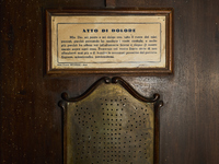 This image shows the exterior of a confessional in the crypt of the San Sabino Cathedral in Bari, Italy. A sign displays the ''Atto di Dolor...