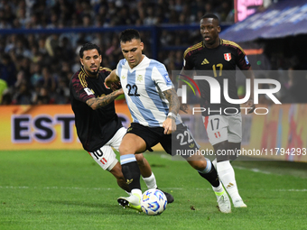 Lautaro Martinez of Argentina plays the ball with Sergio Pena and Luis Advincula of Peru during the match between Argentina and Peru at Albe...