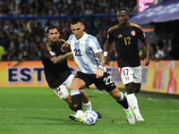 Lautaro Martinez of Argentina plays the ball with Sergio Pena and Luis Advincula of Peru during the match between Argentina and Peru at Albe...