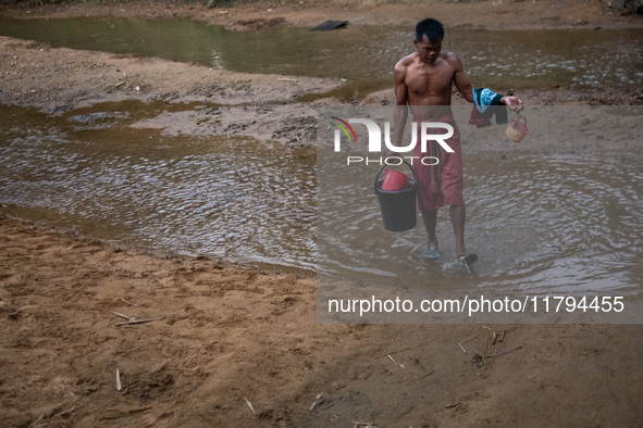 A Bangladeshi tribal man returns home after bathing in a reservoir locally called ''Jhiri,'' which serves as a vital source of clean water f...