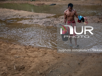 A Bangladeshi tribal man returns home after bathing in a reservoir locally called ''Jhiri,'' which serves as a vital source of clean water f...