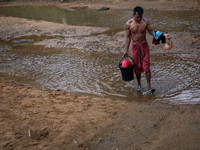 A Bangladeshi tribal man returns home after bathing in a reservoir locally called ''Jhiri,'' which serves as a vital source of clean water f...