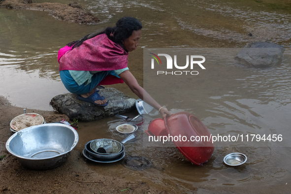 A tribal woman cleans dishes in a reservoir locally called ''Jhiri,'' which serves as a vital source of clean water for the locals in Durgap...