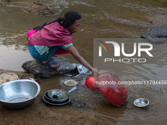 A tribal woman cleans dishes in a reservoir locally called ''Jhiri,'' which serves as a vital source of clean water for the locals in Durgap...