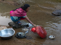 A tribal woman cleans dishes in a reservoir locally called ''Jhiri,'' which serves as a vital source of clean water for the locals in Durgap...