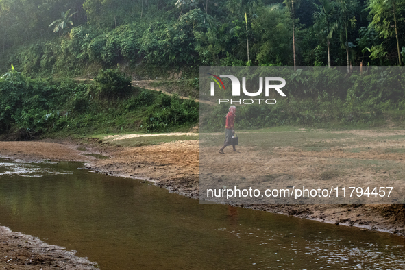 A man carries water in jars from a reservoir locally called ''Jhiri,'' which serves as a vital source of clean water for the locals in Durga...