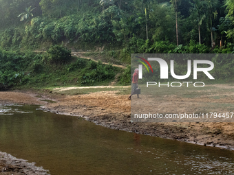 A man carries water in jars from a reservoir locally called ''Jhiri,'' which serves as a vital source of clean water for the locals in Durga...