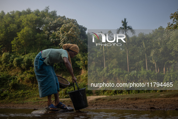 A tribal woman collects water in a jar from a reservoir, locally known as ''Jhiri,'' in Durgapur, Netrokona, Bangladesh, on November 17, 202...