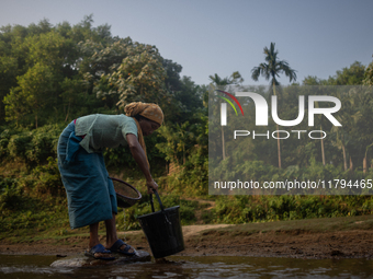 A tribal woman collects water in a jar from a reservoir, locally known as ''Jhiri,'' in Durgapur, Netrokona, Bangladesh, on November 17, 202...