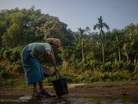 A tribal woman collects water in a jar from a reservoir, locally known as ''Jhiri,'' in Durgapur, Netrokona, Bangladesh, on November 17, 202...