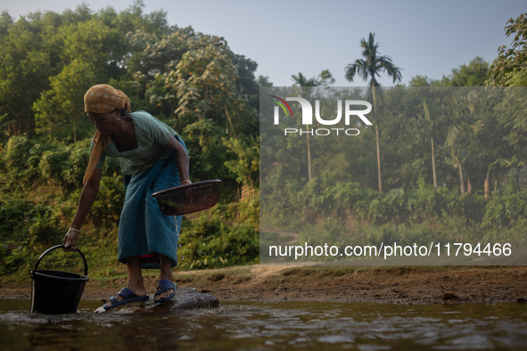 A tribal woman collects water in a jar from a reservoir, locally known as ''Jhiri,'' in Durgapur, Netrokona, Bangladesh, on November 17, 202...