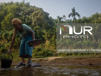 A tribal woman collects water in a jar from a reservoir, locally known as ''Jhiri,'' in Durgapur, Netrokona, Bangladesh, on November 17, 202...