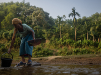 A tribal woman collects water in a jar from a reservoir, locally known as ''Jhiri,'' in Durgapur, Netrokona, Bangladesh, on November 17, 202...