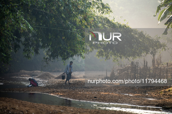 A man carries water in jars from a reservoir locally called ''Jhiri,'' which serves as a vital source of clean water for the locals in Durga...