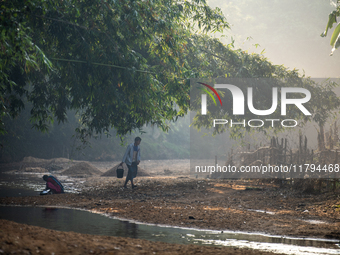 A man carries water in jars from a reservoir locally called ''Jhiri,'' which serves as a vital source of clean water for the locals in Durga...