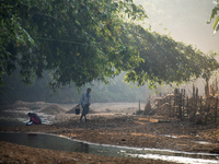 A man carries water in jars from a reservoir locally called ''Jhiri,'' which serves as a vital source of clean water for the locals in Durga...