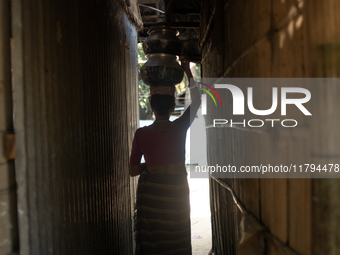 A tribal woman heads home after collecting water from the reservoir, locally known as ''Jhiri,'' in Durgapur, Netrokona, Bangladesh, on Nove...