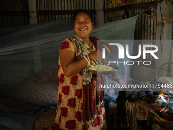 A tribal woman reacts to the camera as she eats her morning meal in Durgapur, Netrokona, Bangladesh, on November 17, 2024. (