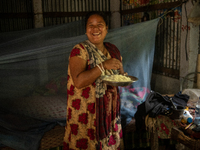 A tribal woman reacts to the camera as she eats her morning meal in Durgapur, Netrokona, Bangladesh, on November 17, 2024. (