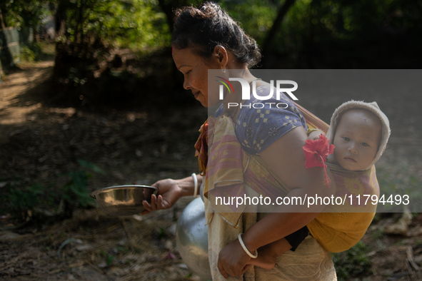 A tribal woman carries her child as she walks towards the reservoir, locally known as ''Jhiri,'' in Durgapur, Netrokona, Bangladesh, on Nove...