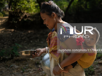 A tribal woman carries her child as she walks towards the reservoir, locally known as ''Jhiri,'' in Durgapur, Netrokona, Bangladesh, on Nove...