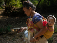 A tribal woman carries her child as she walks towards the reservoir, locally known as ''Jhiri,'' in Durgapur, Netrokona, Bangladesh, on Nove...