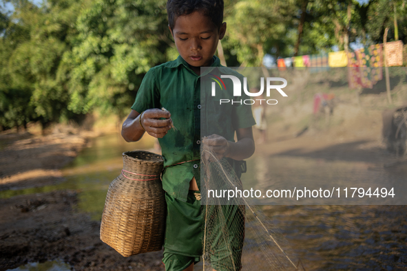 Indrajit (11) catches fish from the reservoir with a small net to support his family in Durgapur, Netrokona, Bangladesh, on November 17, 202...