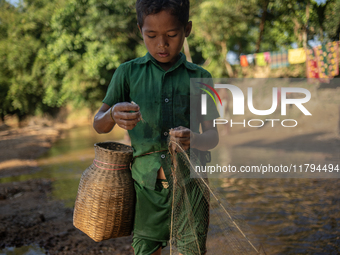 Indrajit (11) catches fish from the reservoir with a small net to support his family in Durgapur, Netrokona, Bangladesh, on November 17, 202...