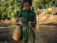 Indrajit (11) catches fish from the reservoir with a small net to support his family in Durgapur, Netrokona, Bangladesh, on November 17, 202...