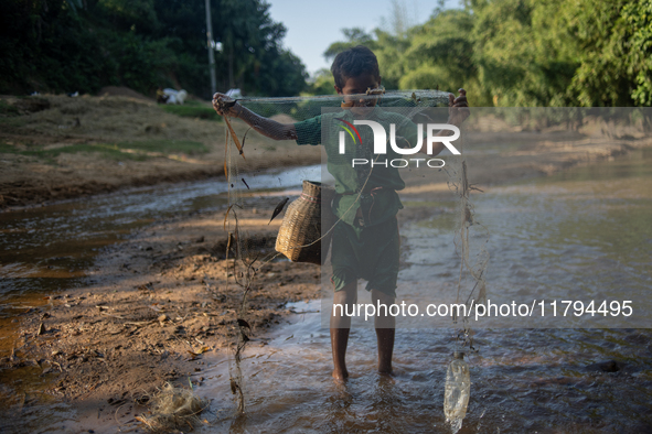 Indrajit (11) catches fish from the reservoir with a small net to support his family in Durgapur, Netrokona, Bangladesh, on November 17, 202...