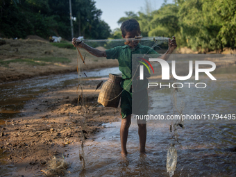 Indrajit (11) catches fish from the reservoir with a small net to support his family in Durgapur, Netrokona, Bangladesh, on November 17, 202...