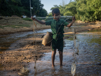 Indrajit (11) catches fish from the reservoir with a small net to support his family in Durgapur, Netrokona, Bangladesh, on November 17, 202...