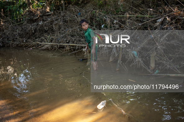 Indrajit (11) catches fish from the reservoir with a small net to support his family in Durgapur, Netrokona, Bangladesh, on November 17, 202...