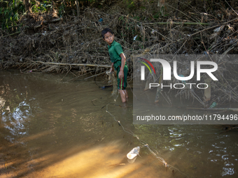 Indrajit (11) catches fish from the reservoir with a small net to support his family in Durgapur, Netrokona, Bangladesh, on November 17, 202...