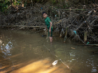 Indrajit (11) catches fish from the reservoir with a small net to support his family in Durgapur, Netrokona, Bangladesh, on November 17, 202...