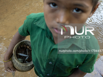 Indrajit (11) catches fish from the reservoir with a small net to support his family in Durgapur, Netrokona, Bangladesh, on November 17, 202...