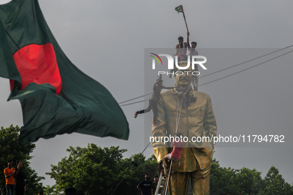 Protesters climb a public monument of Sheikh Mujibur Rahman as they celebrate the news of Prime Minister Sheikh Hasina's resignation in Dhak...