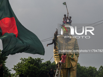 Protesters climb a public monument of Sheikh Mujibur Rahman as they celebrate the news of Prime Minister Sheikh Hasina's resignation in Dhak...