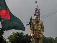 Protesters climb a public monument of Sheikh Mujibur Rahman as they celebrate the news of Prime Minister Sheikh Hasina's resignation in Dhak...